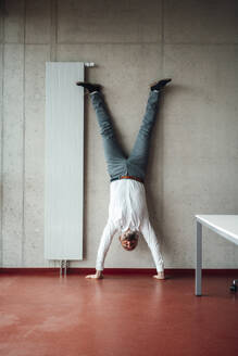 Geschäftsmann übt Handstand im Büro - JOSEF20241