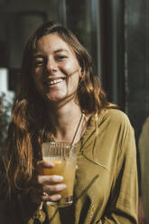 Smiling young woman holding glass of juice - JOSEF20268