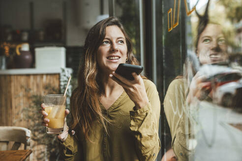 Glückliche junge Frau, die in einem Café mit einem Smartphone telefoniert - JOSEF20273