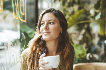 Thoughtful young woman with coffee cup in cafe - JOSEF20279