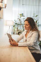 Smiling young businesswoman using tablet PC at desk - JOSEF20324