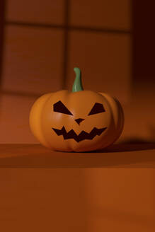 Plastic jack o lantern lying against orange background - MSMF00064