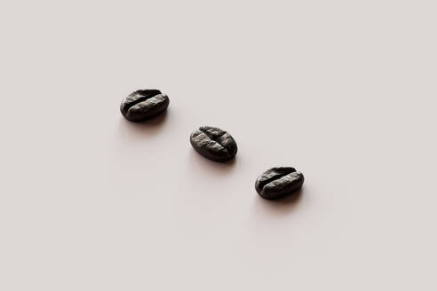 3D render of three roasted coffee beans lying against white background - GCAF00380