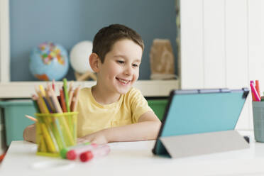 Happy boy studying and using tablet PC at home - ONAF00588