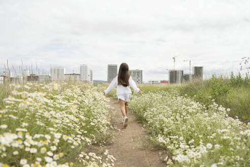 Carefree girl running amidst daisy plants in meadow - LESF00375