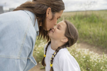 Mother kissing happy daughter in nature - LESF00386