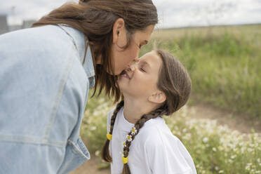 Mutter küsst glückliche Tochter in der Natur - LESF00386