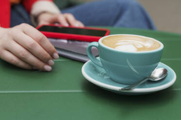 Woman with coffee cup and smart phone at table - OSF01914