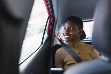 Happy young woman sitting in car - PNAF05763