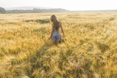 Mädchen mit langen Haaren geht in einem Weizenfeld - AAZF00796