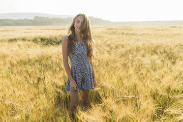 Lächelndes Mädchen inmitten einer Weizenernte auf einem Feld - AAZF00804