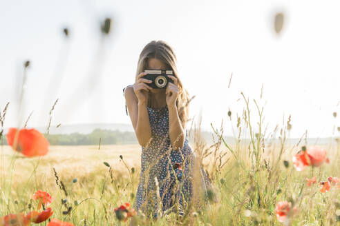 Mädchen fotografiert mit Kamera in Mohnfeld - AAZF00829