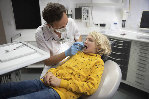 Zahnarzt untersucht die Zähne eines blonden Jungen in einer medizinischen Klinik - NJAF00447