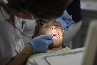 Zahnarzt untersucht die Zähne eines Patienten mit Werkzeugen in der Klinik - NJAF00451