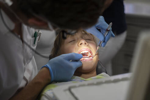 Dentist examining patient's teeth with tools at clinic - NJAF00451