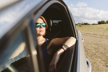 Kontemplative Frau im Auto sitzend an einem sonnigen Tag - SIF00727