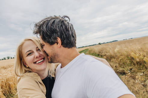 Lächelndes, sich umarmendes Paar in einem Weizenfeld - VSNF01243