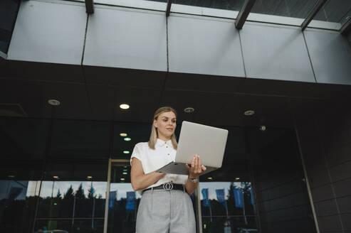 Geschäftsfrau mit Laptop vor einem Gebäude - ALKF00418