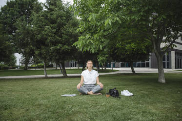 Businesswoman meditating in office park - ALKF00440