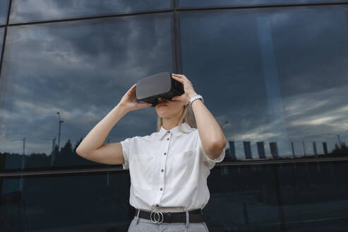 Geschäftsfrau mit Virtual-Reality-Simulator vor einer Glasscheibe - ALKF00463