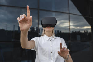 Geschäftsfrau gestikuliert mit Virtual-Reality-Simulator - ALKF00465