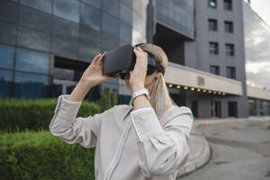 Geschäftsfrau trägt Virtual-Reality-Simulatoren im Büropark - ALKF00479
