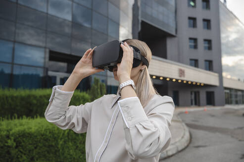 Businesswoman wearing virtual reality simulators in office park - ALKF00479