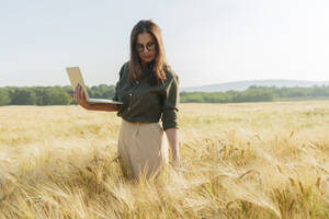 Agronom mit Laptop und Untersuchung der Gerstenkulturen auf dem Feld - AAZF00863