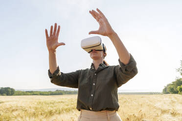 Businesswoman gesturing with virtual reality simulator at farm - AAZF00898