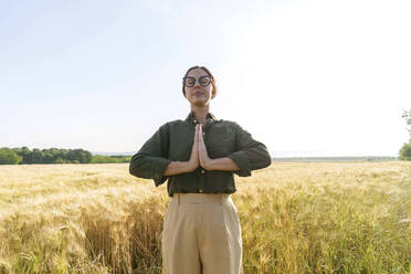 Geschäftsfrau beim Meditieren inmitten von Weizenpflanzen auf einem Feld - AAZF00902