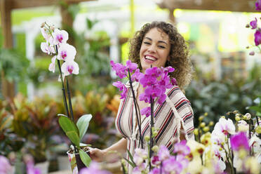 Glückliche Frau lachend inmitten von Blumen in einer Gärtnerei - JSMF02814