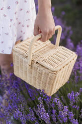 Young woman holding wicker basket in lavender field - ONAF00604