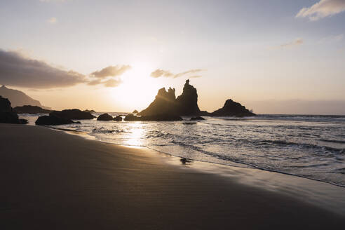 Silhouette von Wellen und Felsen am Strand bei Sonnenuntergang - PNAF05865