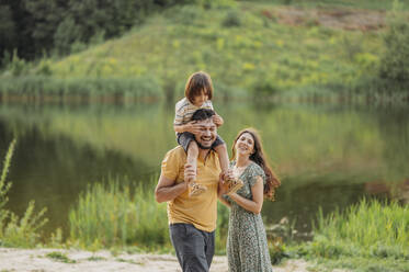 Happy parents enjoying with son near lake - ANAF01822