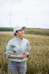 Thoughtful agronomist standing with laptop in wheat field - EKGF00362