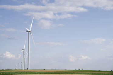 Windkraftanlagen unter bewölktem Himmel an einem sonnigen Tag - EKGF00371