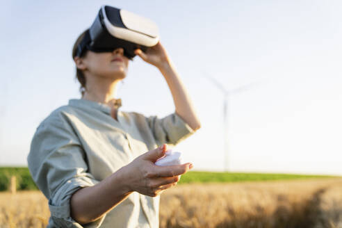 Hand eines Landwirts, der ein Virtual-Reality-Headset in einem Weizenfeld bedient - EKGF00418