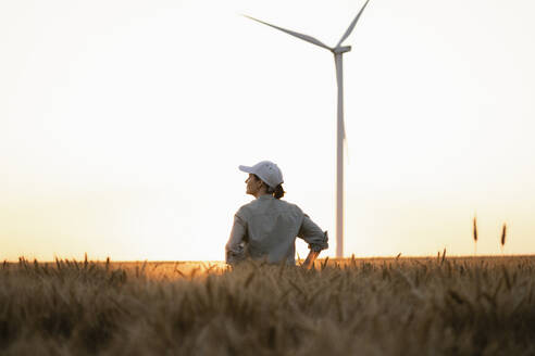 Landwirt auf einem Feld mit einer Windkraftanlage im Hintergrund - EKGF00428