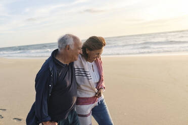 Happy senior couple together walking at beach - ASGF04091