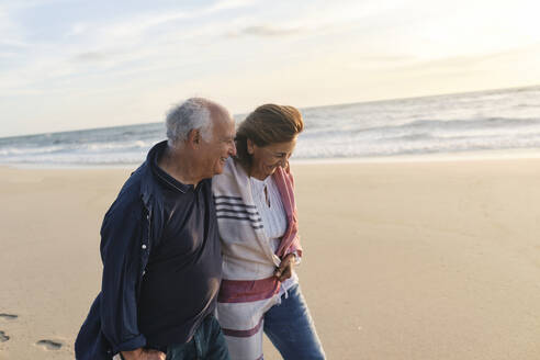 Glückliches älteres Paar, das gemeinsam am Strand spazieren geht - ASGF04091