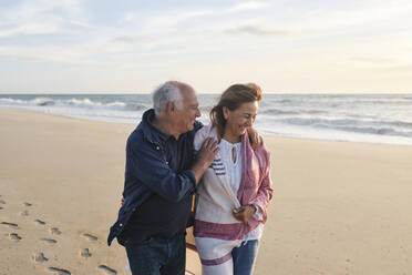 Glückliches älteres Paar, das gemeinsam am Strand spazieren geht - ASGF04094