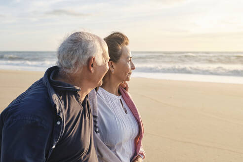Lächelndes älteres Paar am Strand an einem sonnigen Tag - ASGF04099