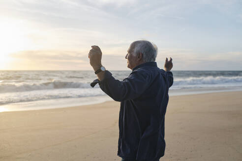 Senior man with arms raised standing at beach - ASGF04115