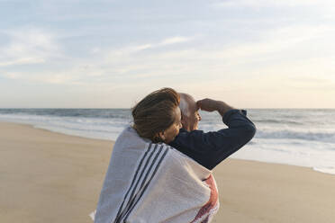 Woman hugging man in front of sea at beach - ASGF04122