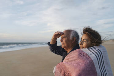 Smiling senior woman hugging man standing at beach - ASGF04124