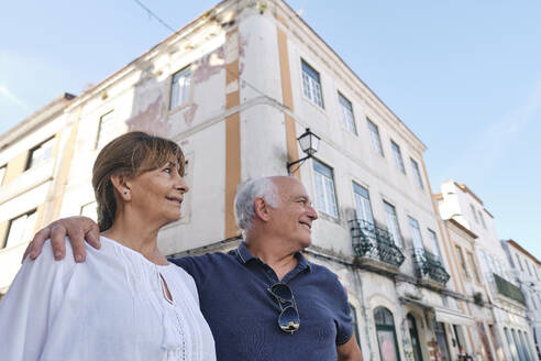 Smiling senior couple standing together in front of buildings - ASGF04170