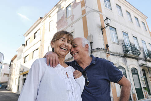 Fröhliche ältere Frau mit Mann vor einem Gebäude stehend - ASGF04173