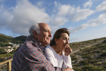 Smiling senior man and woman under cloudy sky on sunny day - ASGF04201