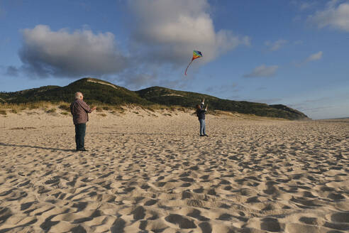 Glückliches älteres Paar lässt am Strand einen Drachen steigen - ASGF04212