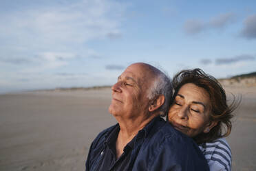 Smiling woman embracing man at beach - ASGF04219